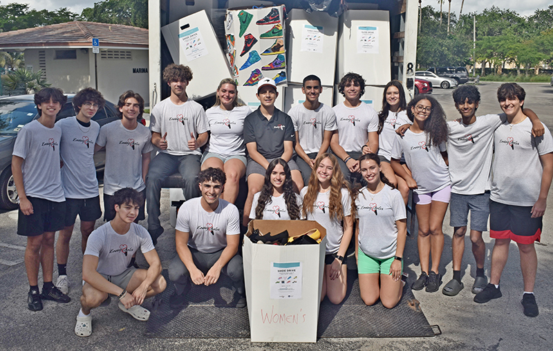 Volunteers with the student-led charity Loving Soles pose May 6, 2024, with some of the 12,000 pairs of shoes they collected for the Camillus House homeless shelter.