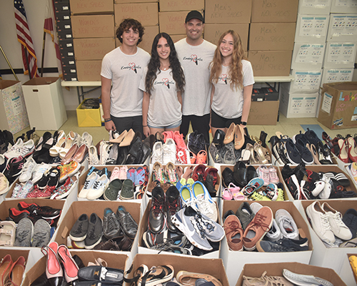 Ramiro Inguanzo, second from right, poses with his children, from left, Christopher, Sophia and Susanna May 6, 2024, with some of the 12,000 pairs of shoes his charity, Loving Soles, collected this year for the Camillus House homeless shelter.