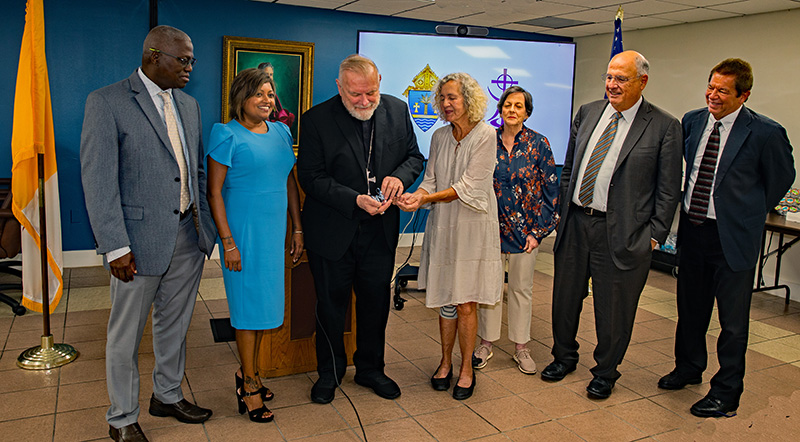 Margarita Aguiar, president of the Ursuline Alumnae Association, center, presents Archbishop Thomas Wenski with the keys to the Ursuline Residence during a ceremony at the Pastoral Center Sept. 3, 2024. Participating in the ceremony were, from left, Jules Jones, chief financial officer of Catholic Charities; Devika Austin, chief administrative officer of Catholic Charities; Amada Alvarino, past president of the Ursuline Alumnae Association, counselor; Rafael Penalver, attorney for the Ursulines; and Peter Routsis-Arroyo, CEO of Catholic Charities.