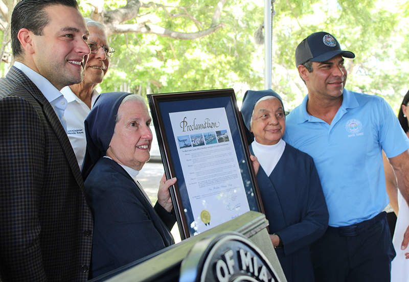 Sor Eva Pérez-Puelles (izquierda) y Sor Juanita Flores, Hijas de la Caridad de San Vicente de Paúl, sostienen una proclama del condado de Miami-Dade que reconoce el 9 de septiembre de 2024 como Día de Sor Hilda Alonso. Acompañan a las hermanas en la foto, desde la izquierda los comisionados de Miami, Kevin Cabrera y Manolo Reyes y el alcalde de la ciudad de Miami, Francis Suárez.