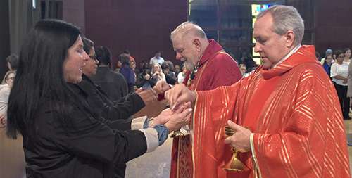 Father Jose Alvarez, foreground, joins Archbishop Thomas Wenski in distributing Communion to the attendees at the annual archdiocesan Catechetical Conference at Epiphany Church, Miami, on Oct. 15, 2024.