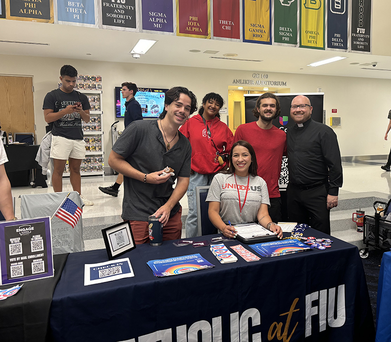 From left to right, Christian Caro, Daliannette Garcia-Pagan, Nicholas Aquino-Guzman, Father Luis Pavon from Catholic campus ministry at Florida International University and seated is Hidana Lopez, a UnidosUS representative, pose for a picture during the National Voter Registration Day event Sept. 17, 2024 at FIU’s Graham Center in Miami. This nonpartisan voter registration drive was organized by the university. Univision, represented by UnidosUS, and campus ministry participated to encourage students to register to vote.