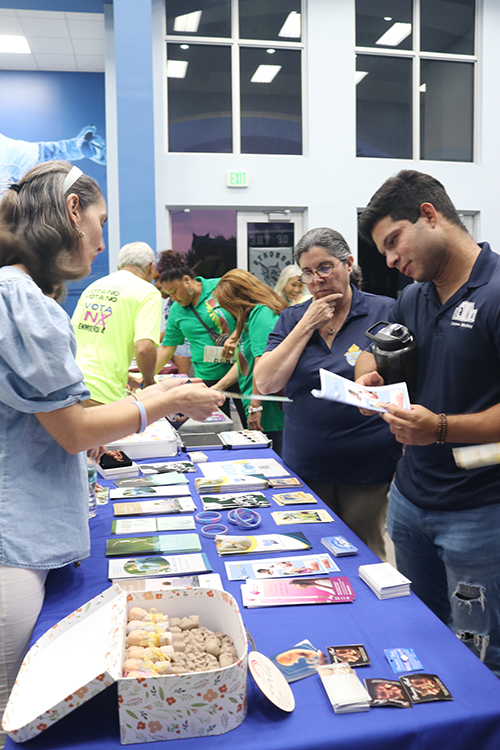 Anibal Valencia, a theology and political science student at St. Thomas University, receives information from Catalina Escobar about the Respect Life Ministry of the Archdiocese of Miami. With them is Belkys Rodríguez Prado, assistant director of the Respect Life Ministry, moments before the start of the Pro-life rally Sept. 27, 2024.