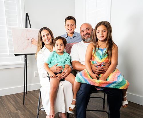 Christie Acosta Mora and her husband John Mora are filmed with their children Myles, first row, Cruz, second row, middle, and Liv, second row, far right, July 28, 2024. The family was filmed for the Archdiocese of Miami’s campaign against Amendment 4. The couple shared the story of their daughter Vida Elyse, who had Trisomy 13 and who had a short life, and they talked about the gifts her life brought to their family and community.