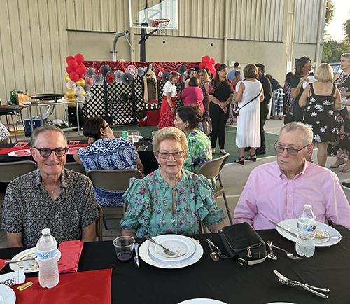 Desde la izquierda, los feligreses de Little Flower en Hollywood, Lyle Hennen y Mary y Kiernan Joyce, disfrutan de una cena de flamenco y paella, el 28 de septiembre de 2024, como parte de la celebración del centenario de la parroquia.