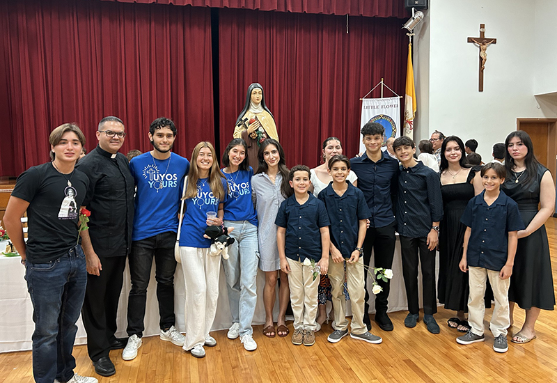 Miembros del grupo de jóvenes de la parroquia St. Katharine Drexel y Tuyos Yours, un grupo del rosario, posan para la foto con el P. Javier Barreto, párroco de la iglesia Little Flower, en Hollywood, después de la Misa del Centenario, el 1º de octubre de 2024.