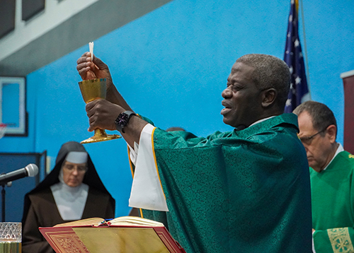 Father Attah Nsiah, chaplain at Archbishop Coleman Carroll High School, celebrates Mass at the induction ceremony for the St. Michael's Scholars Program at the school's gymnasium Oct. 24.