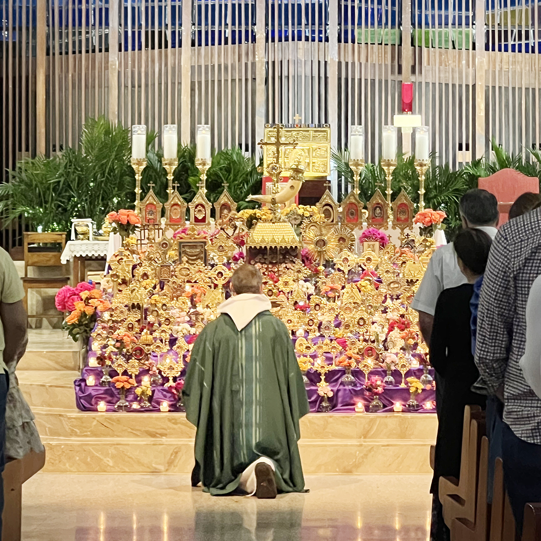 Visiting from Brazil, Father Felippe Roche kneels before the altar adorned with more than 400 sacred relics at the 5:30 pm Mass November 3, which coincided with the Exposition and Veneration of Sacred Relics Exhibition.