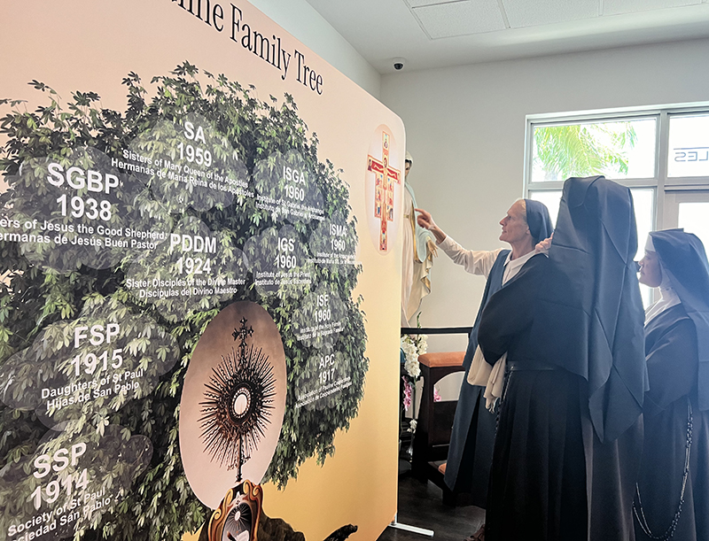 Daughter of St. Paul Sister Irene Regina Hoernschemeyer shows the Carmelite Sisters of the Most Sacred Heart of Los Angeles the display she created, celebrating the branches of the Pauline family during the Daughters of St. Paul’s 65-year anniversary in Miami reception. The Mass and reception took place Nov. 3, 2024 at Our Lady of Guadalupe Parish in Doral.