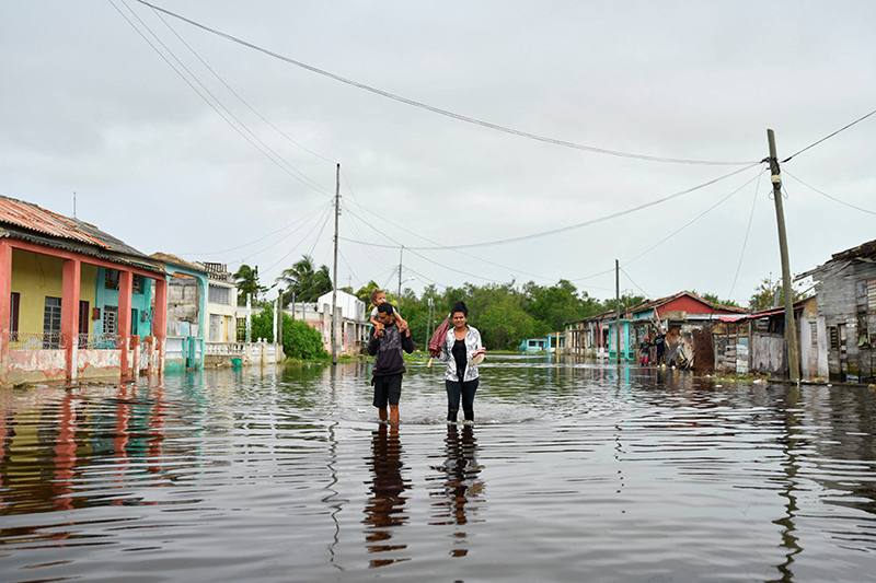 A family walks down a flooded street a day after Hurricane Rafael made landfall in Batabano, Cuba, Nov. 7, 2024. The Cuban people are suffering immense hardship after a series of natural disasters in recent weeks, the collapse of the electrical system and food shortages.