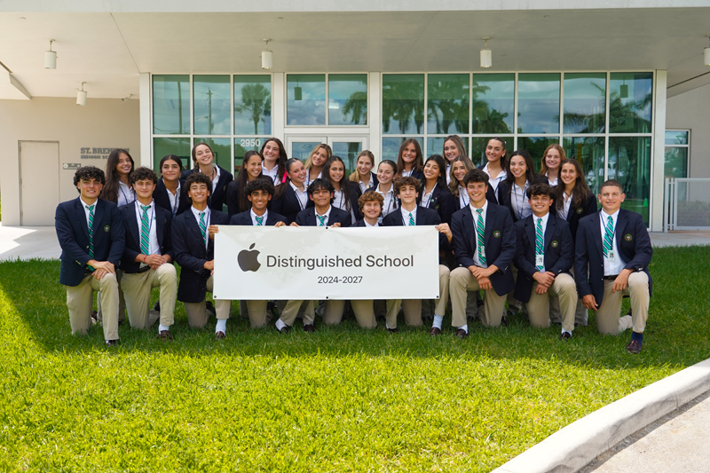 St. Brendan High students pose with their Apple Distinguished School banner after being named an Apple Distinguished School in August 2024 for their innovation, leadership and educational excellence. They join five other Archdiocese of Miami Catholic Schools that hold the distinction.