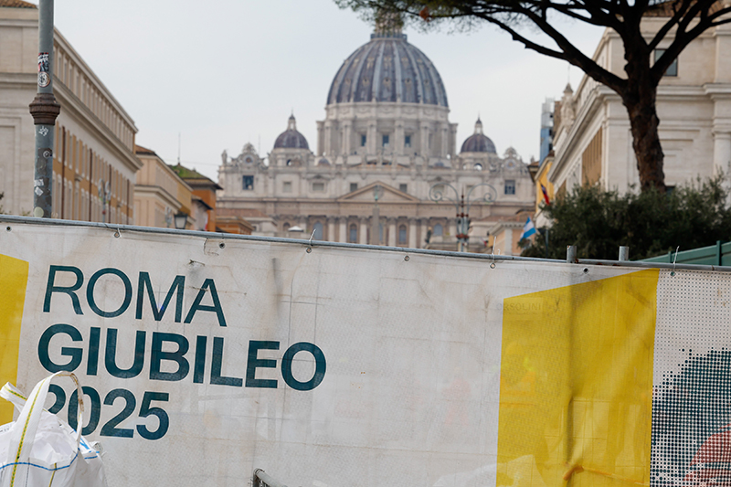 The dome of St. Peter's Basilica is seen over a cloth barricade reading "Rome Jubilee 2025" that surrounds a construction site at the beginning of the broad boulevard leading to St. Peter's Square Dec. 4, 2024. The city of Rome is preparing for the Holy Year with hundreds of roadworks and restoration projects. (CNS photo/Lola Gomez)