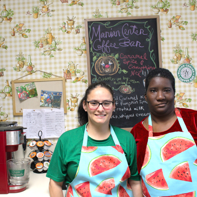 Amanda Lambert and Shanece Joseph, clients of the Marian Center's Adult Day Training Program, pose by the Marian Center Coffee Bar. Both are learning different coffee barista skills to serve various coffees and teas.