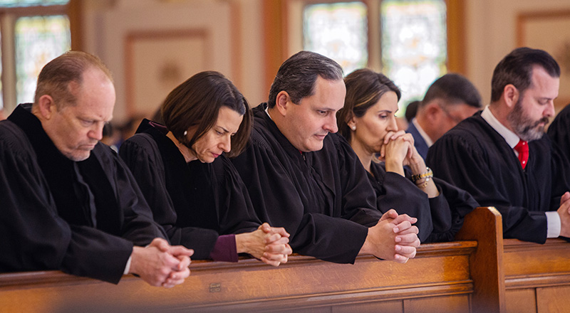 Judges pray during the annual Red Mass celebrated by Archbishop Thomas Wenski at Gesu Church of Miami on Dec. 11, 2024.