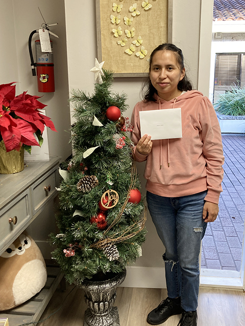 Jakelin Gabriel, one of the recipients of the 2023 Heart of Christmas gifts poses with her gift card at the South Dade office of Respect Life Pregnancy Help Center. The gifts were given out the week before Christmas. The program is conducted each year by the archdiocesan Office of Development, which requests applications from parishes, schools and Catholic Charities agencies in the Archdiocese of Miami.