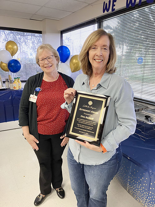 Dian Backoff, right, receives a plaque from Mary Jo Frick, president and CEO of Catholic Health Services, at her retirement breakfast Dec. 20, 2024, in recognition of her outstanding service as executive director of Catholic Hospice since 2018.  The event was attended by leadership and staff from Catholic Hospice, Catholic Health Services and Home Health Services.