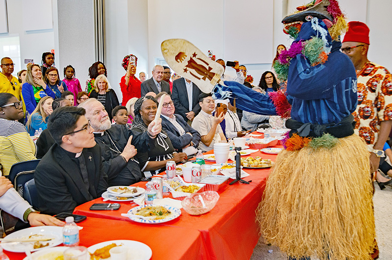 A Nigerian dancer exchanges greetings with Archbishop Thomas Wenski during a traditional Nigerian dance. The holders of the hand fan and elephant tusk use them, instead of handshake with fellow elders, as a greeting. Cultural groups got together following the annual Migration Mass, featuring multicultural foods and folkloric dances from the various ethnic groups. Archbishop Wenski celebrated the Mass Jan. 5, 2025, feast of the Epiphany, at St. Mary Cathedral.