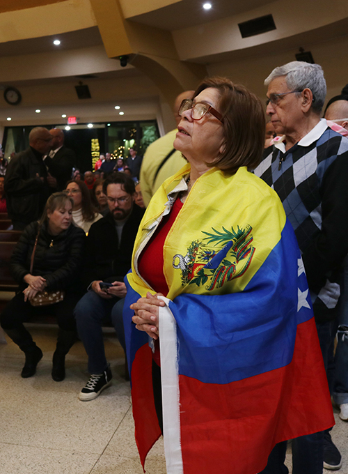 Envuelta en su bandera, una venezolana reza por su país en la Misa por Venezuela que se realizó en la Ermita de la Caridad, el 9 de enero de 2025.