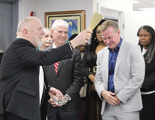 Archbishop Thomas Wenski sprinkles holy water over the staff of Catholic Legal Services at the blessing ceremony of its new Miami location on January 15, 2025.