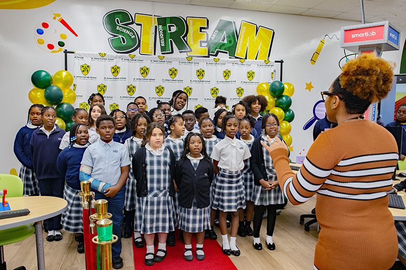 Alisha Durena, a 5th-grade teacher's aide, leads the St. James School Angel Choir in singing 'I Trust in God' during the dedication of the school's new SmartLab in North Miami