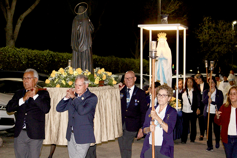 Hospitalité de Miami members Luis Espinosa (left), Joel Merz, and Fernando Rios carry a statue of St. Bernadette (front) during the Lourdes Candlelight Procession Feb. 11, 2025, accompanied by Monica Cacciaguida who holds the torch. Other members carry a statue of Our Lady of Lourdes (back) during the event held at Our Lady of Lourdes Parish on the feast day.