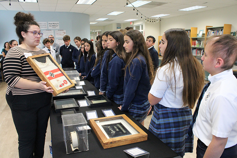 Alberta Salinas, who works with the nonprofit Hate Ends Now Holocaust immersive education, shows a Nazi youth athletic uniform to seventh graders at St. Louis Covenant School. Other artefacts related to the Holocaust and Nazism are part of the collection shown to students during Holocaust Remembrance Day at St. Louis School held March 3, 2025.