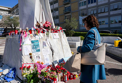 A woman stands near a statue of St. John Paul II outside Rome’s Gemelli hospital March 6, 2025, looking at messages and drawings for Pope Francis, who has been hospitalized there since Feb. 14, receiving treatment for double pneumonia.