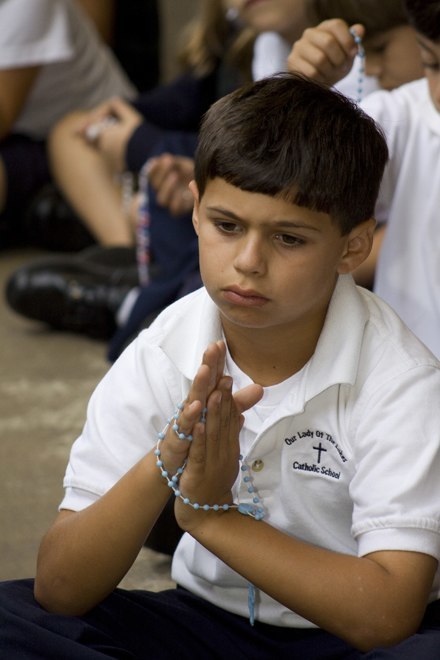 Second grader Adrian Vega prays the rosary.