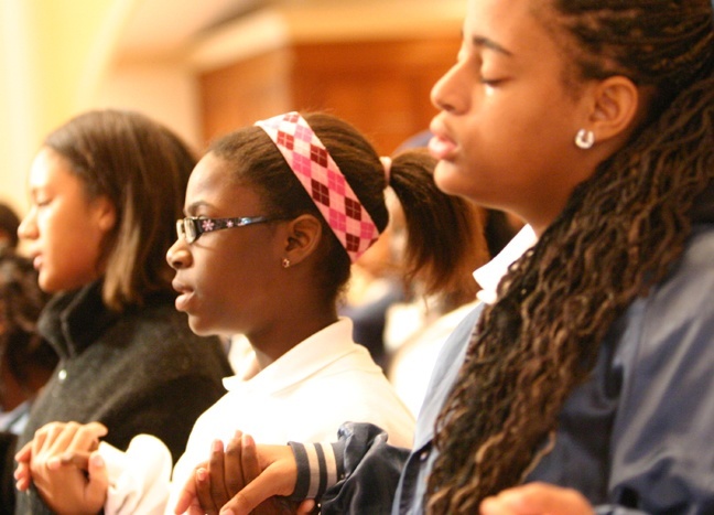 Carmen Pierre, right, and Sandrine Basquin, seventh-graders at St. Mary Cathedral School, pray the Our Father during the Mass Jan. 13 for victims of the earthquake in Haiti.