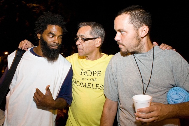 Hector Gonzalez, founder of Hope for Homeless, talks with homeless men during a recent sandwich distribution run in downtown Miami.