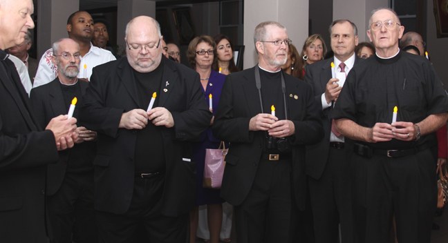 Members of the Little Brothers of the Good Shepherd, who staff Camillus House, hold their candles during the vigil that followed the Mass at Gesu Church Jan. 19.