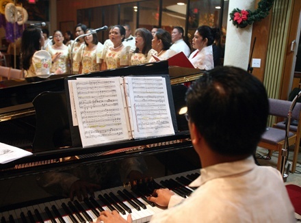 Harold Dioquino, playing the piano, directs the Dinggin choir during the Mass.