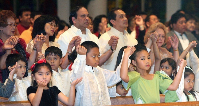 Filipino Catholics pray the Our Father during the Mass.