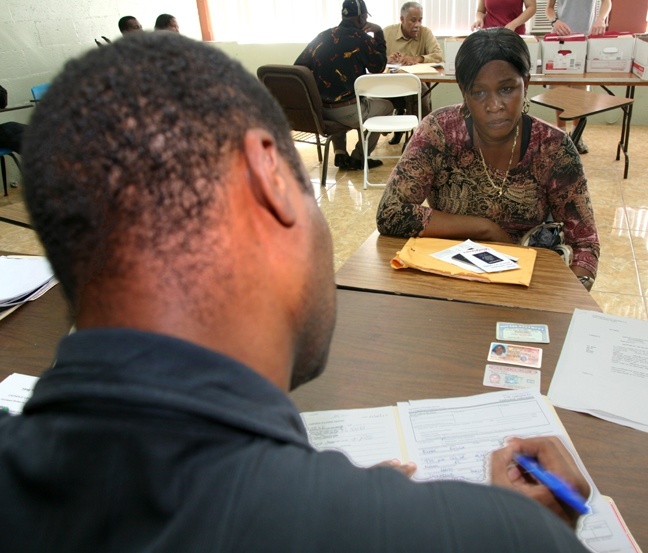 Volunteer Reynald Jean helps Rosilia Pierre fill out a form for Temporary Protected Status at Notre Dame d'Haiti Church Jan. 22.