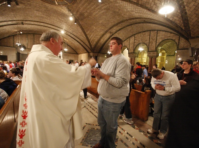 Father Richard Mullen distributes Communion to the teenagers in the crypt-level of the National Shrine of the Immaculate Conception. The delegations from the Archdiocese of Miami and Archdiocese of Omaha celebrated Mass together.