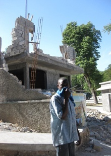 A man covers his face to ward off the smell as he walks by a crumbling building in Port-au-Prince a few days after the 7.0 earthquake.