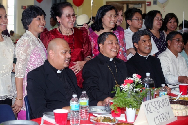 Father Sammy Alvero, Archbishop Bernardito Auza, papal nuncio to Haiti, and Father Jets Medina pose for photos with members of the Filipino Apostolate after the Mass.