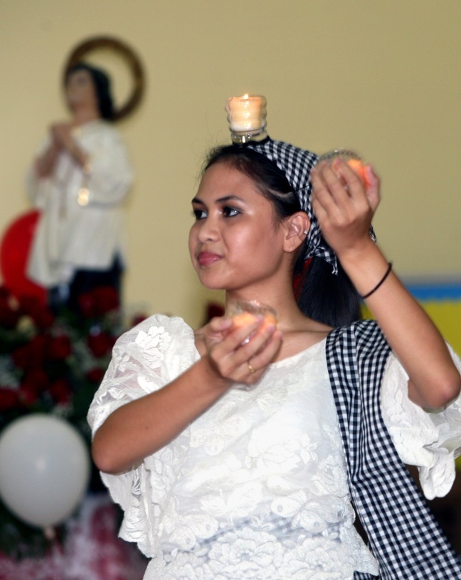 Rossamina Tumulak, of the Sinulog dance group, performs the candle dance with other members of the group during the reception that followed the Mass.