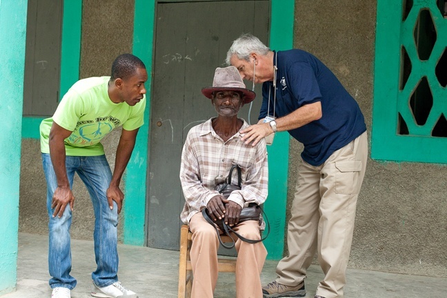 A volunteer doctor with Miami Medical Team examines a man at Our Lady of Mount Carmel Parish in Cayes-Jacmel, Haiti during a recent mission trip. At left is Father Fritzner Bellonce of St. Elizabeth of Hungary Parish in Pompano Beach.