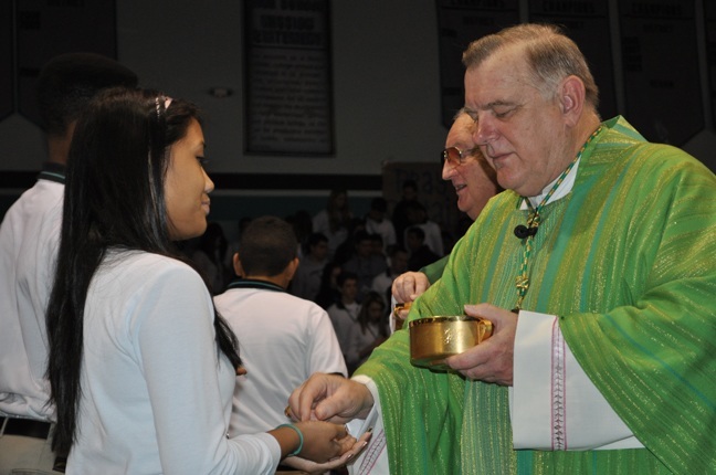 Archbishop Thomas Wenski gives Communion to an Archbishop McCarthy High School student during a Mass Jan. 11 dedicated to the victims of last years earthquake in Haiti and to supporting the Respect Life ministry in the archdiocese.