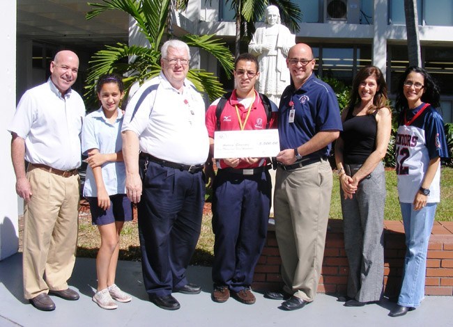 Lucky winner of the Chaminade-Madonna Gala Auction Grand Raffle, senior Andrew Eduartez (center) and his family with the school president, Marianist Father  Larry Doersching, (third from left), Senior Director of Advancement Richard Pulido (third from right), and Principal Teresita Wardlow (far right).