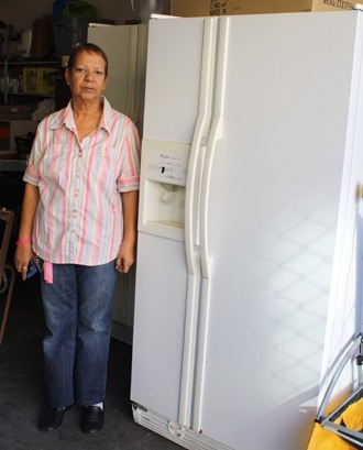 Pilar Rodriguez, manager of the St. Vincent de Paul Society's Hialeah thrift store, poses next to one of the appliances that can be given to the poor or sold to help the poor.