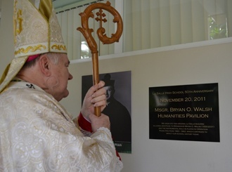 El Arzobispo Thomas Wenski mira la placa en memoria de Mons. Bryan O. Walsh que fue instalada en el edificio original de la Escuela Secundaria La Salle.