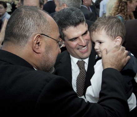 Deacon Victor Pimentel, left, director of the Office of the Permanent Diaconate, congratulates newly-ordained Deacon Guillermo Dutra who is holding his son, Lucas, 14 months old.