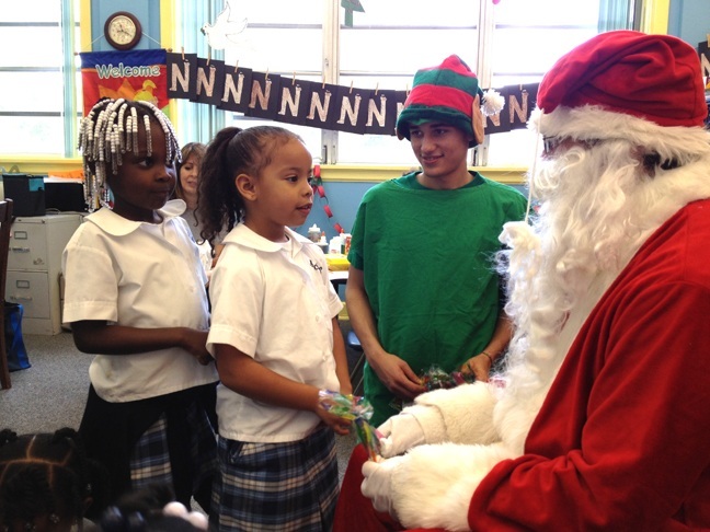 Carroll High students Zachary Estela and Eli Monzon, dressed up as Santa Claus and a helpful elf, listen to the wish list of St. Mary Cathedral School's younger students.