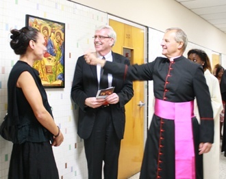 Artist Irena Gapkovska and James Conley, interim dean of Biscayne College, watch as Msgr. Franklyn Casale, president of St. Thomas University, blesses the icon Gapkovska created for the rededicated Kennedy Hall.