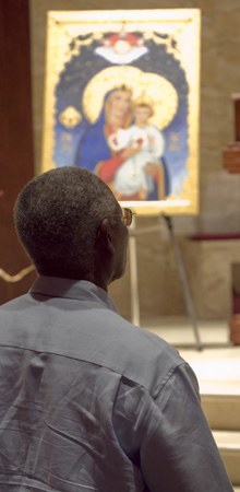 Joseph Bonnaig of St. Andrew Parish kneels during the consecration; the United Hearts Icon is in the background.