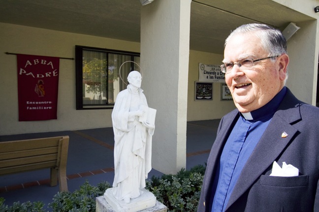 Jesuit Father Marcelino Garcia poses on the grounds of Casa Manresa, the home for Encuentros Familiares and the Ignatian Spirituality Center. Behind him is a statue of St. Ignatius of Loyola, founder of the Jesuits and creator of the spiritual exercises named after him.