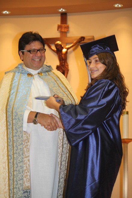 Sabrina Cabrera receives her diploma from Father Jaime Acevedo.