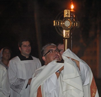 Father Roberto Garza carries the Monstrance in the Procession from the St. Raphael Chapel to St. Brendan High School gymnasium.